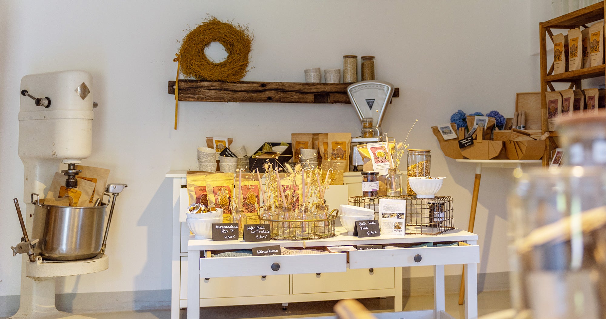 Hofladen von Innen mit Haferprodukten und Accessoires auf einem dekorierten weißen Tisch präsentiert.